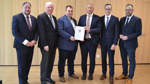 Heimatschutzminister Roman Poseck überreicht dem Mainhauser Bürgermeister Frank Simon den Zuwendungsbescheid aus dem Sofortprogramm „Sicherheit bei Veranstaltungen“; rechts davon der Hainburger Bürgermeister Christian Spahn